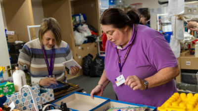 Elaine and another person sorting through item donations at the charity shop