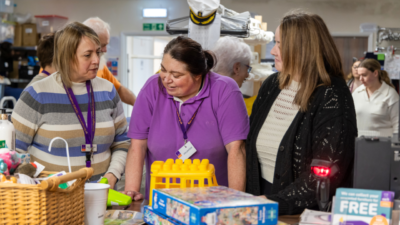 Elaine sorting through items at EACH charity shop with two other people