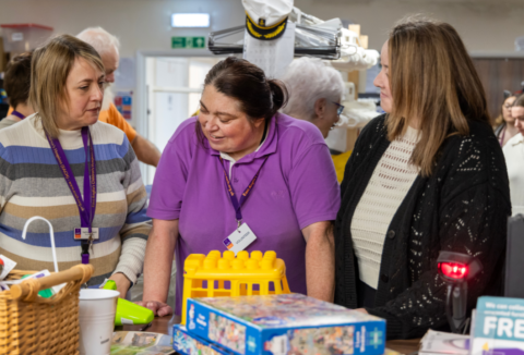 Elaine sorting through items at EACH charity shop with two other people