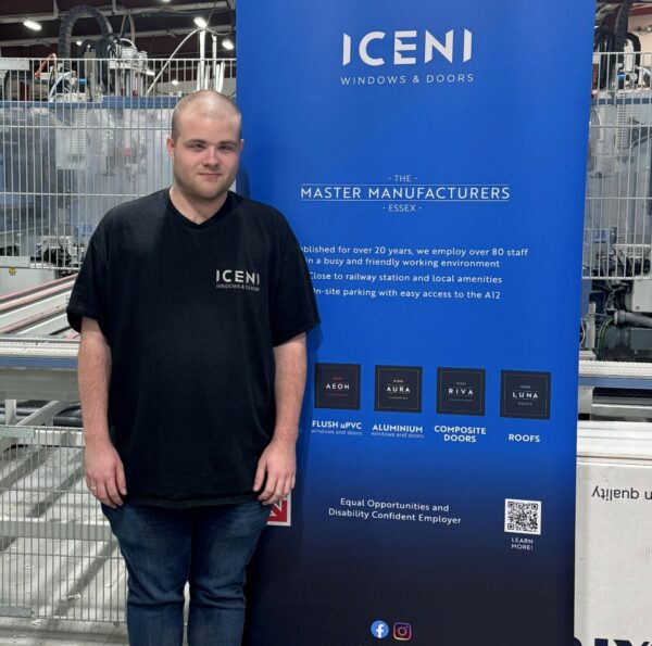 A young man standing next to a blue banner that shows Iceni's logo