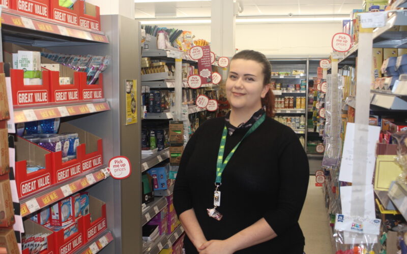 A woman standing in an isle in a shop.