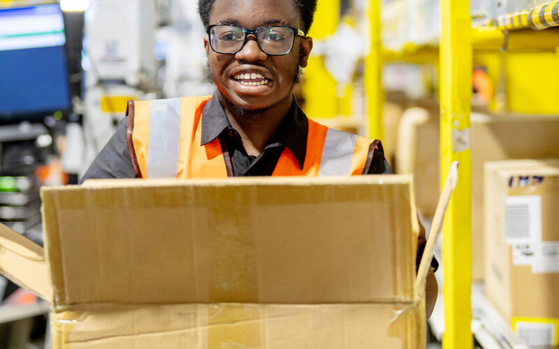 Supported internship graduate Timi at work in Amazon's Tilbury Fulfilment Centre.