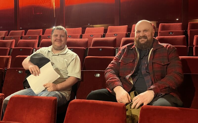 Two young men sat in the audience in an empty theatre.