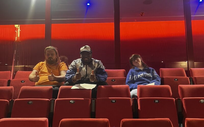 Two young men and a young woman sat in the audience in an empty theatre