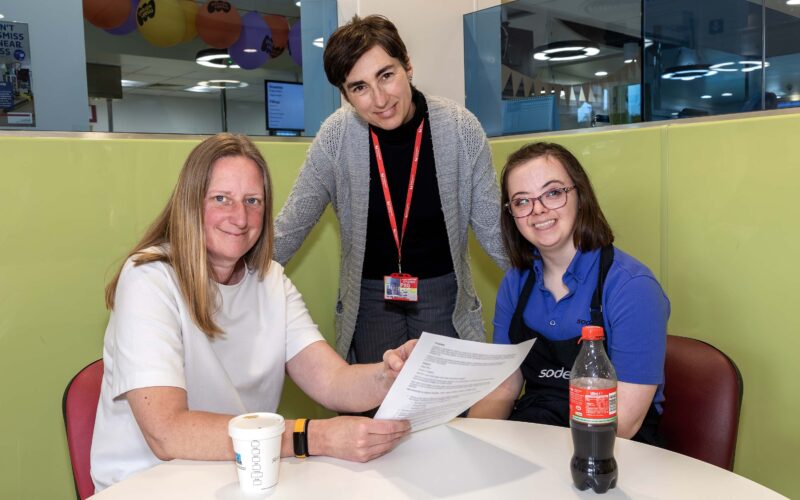 Three ladies sat at a table having a meeting
