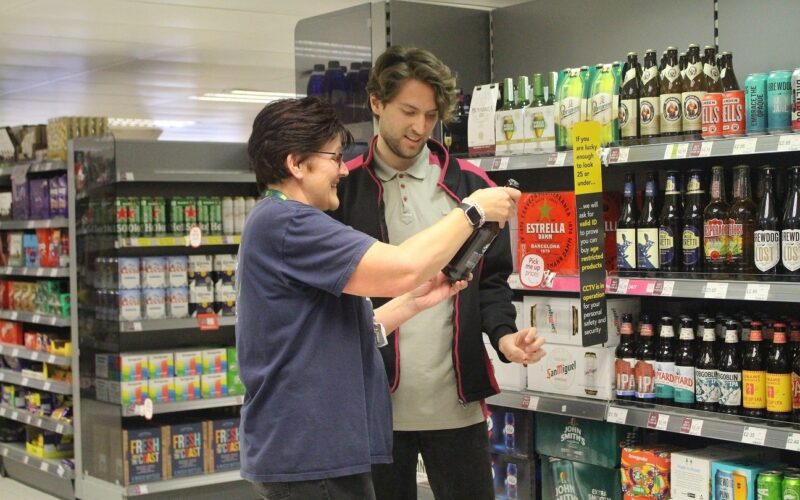 A man and a woman looking at a bottle of wine in Coop.