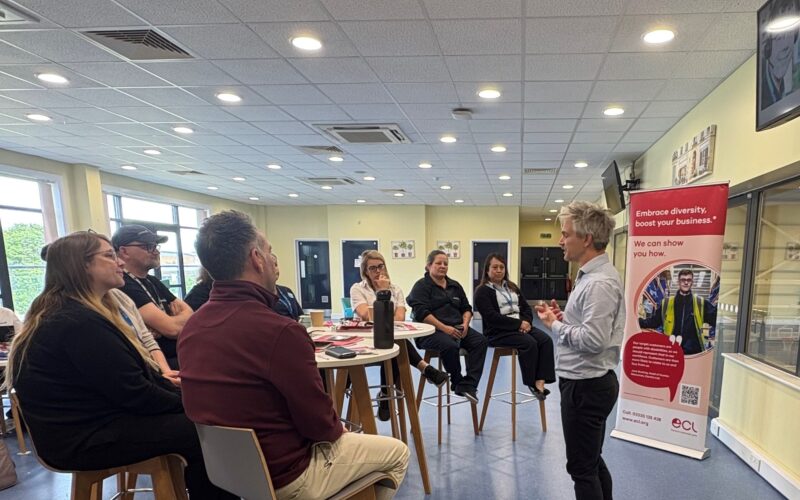 Group of Sodexo staff participating in a training workshop led by a man standing in front of an ECL promotional banner.