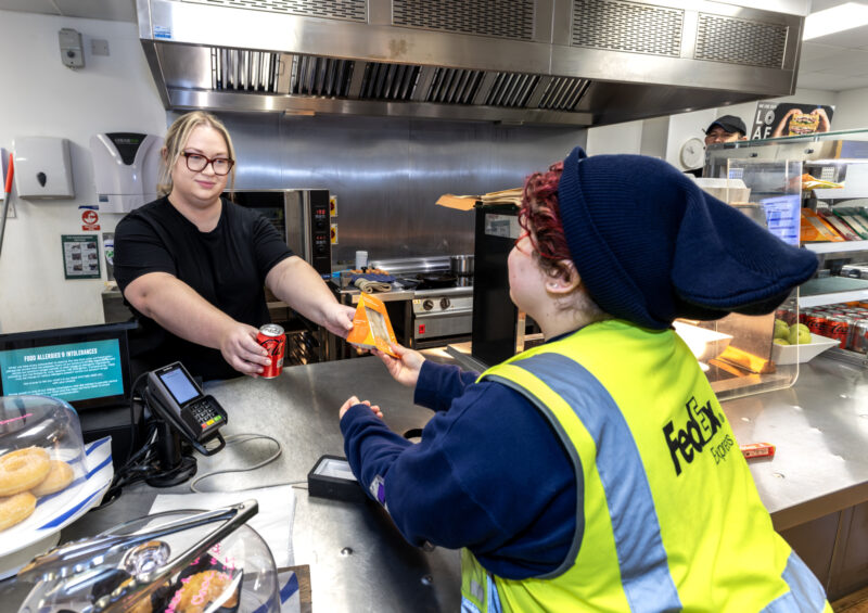 A person receiving lunch from a kitchen worker at their workplace