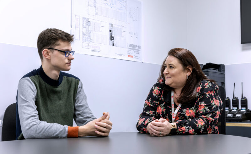 Young man sitting next to an interviewer.