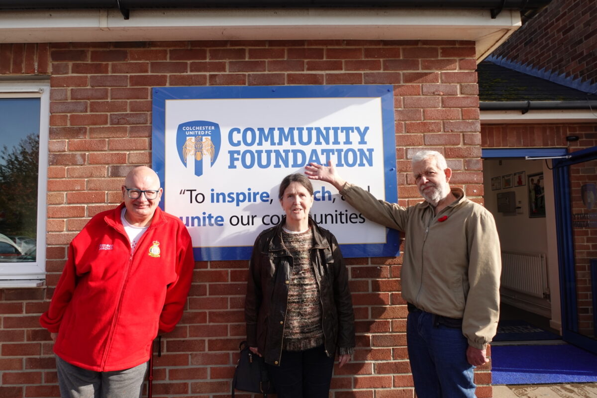 Three ECL customers standing in front of Colchester Community Foundation signage smiling