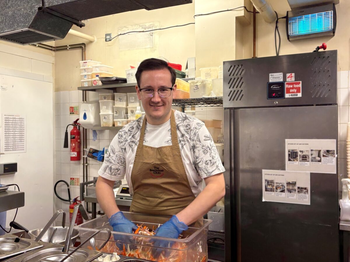 Young man with glasses working in a restaurant kitchen.