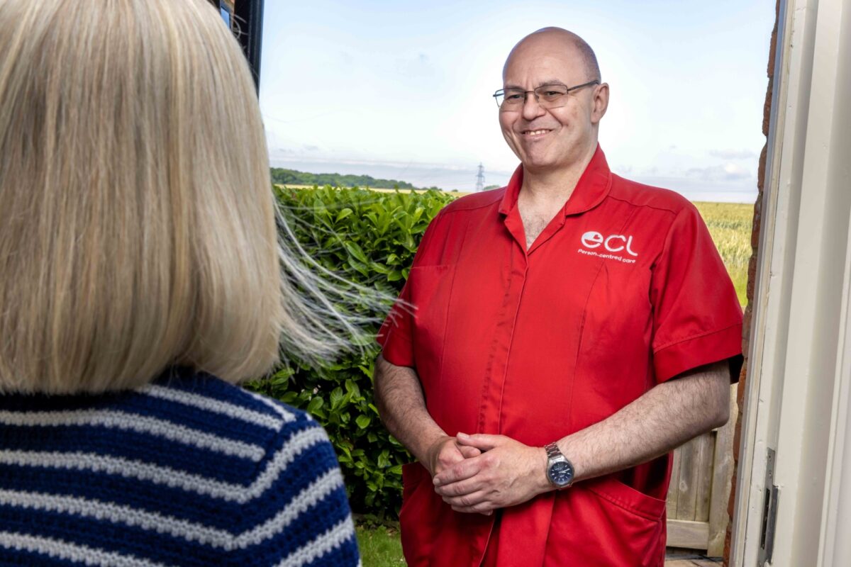 Male ECL carer in red uniform at front door of female customer.