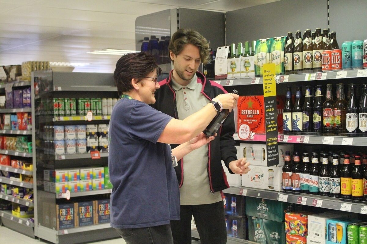 A man and a woman looking at a bottle of wine in Coop.