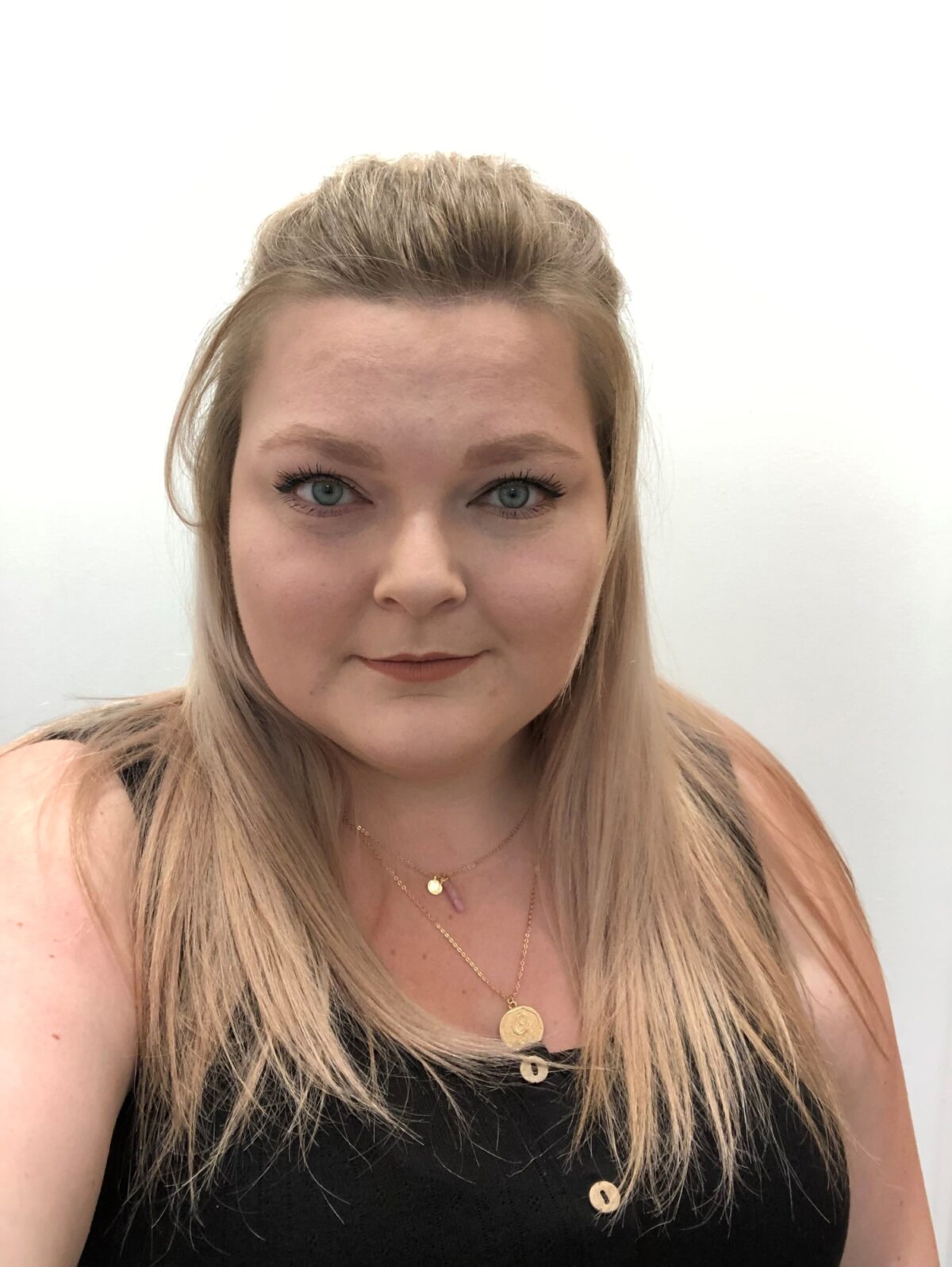 A blonde woman wearing a black tank top looking at the camera