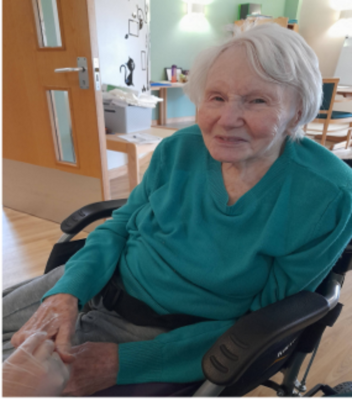 Lady smiling in a wheelchair at a day centre.