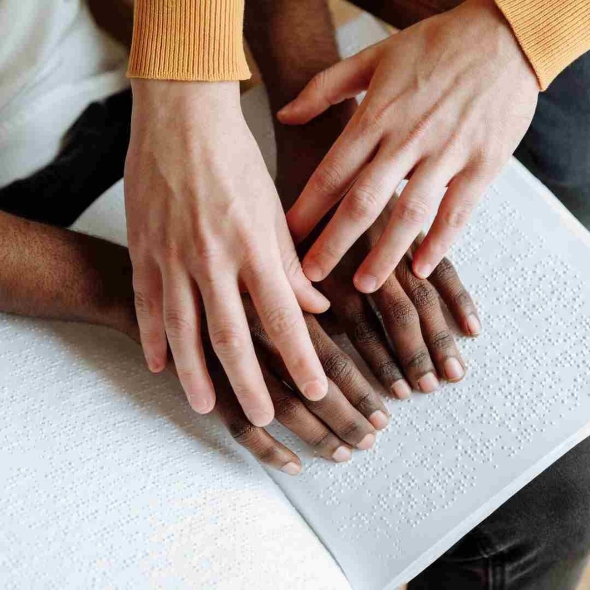 A person helping another person read braille