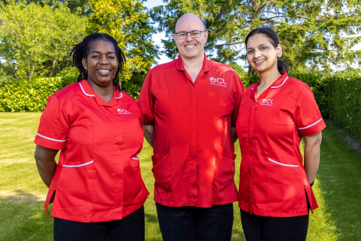 Two female and a male care worker in red ECL uniforms