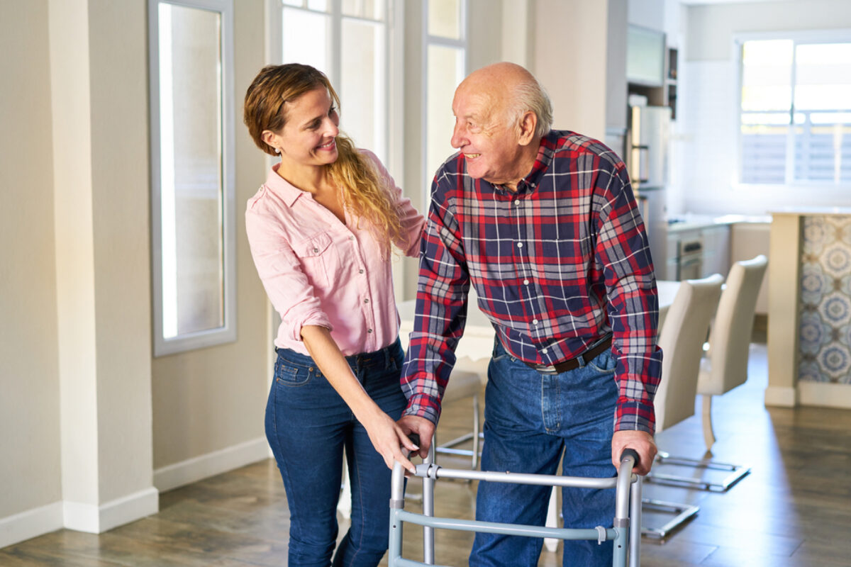 A woman helping an elderly man walk