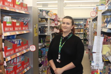 A woman standing in an isle in a shop.