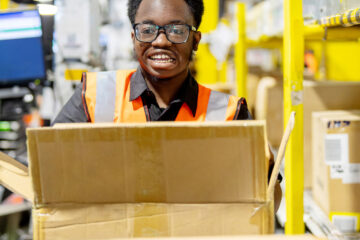 Supported internship graduate Timi at work in Amazon's Tilbury Fulfilment Centre.