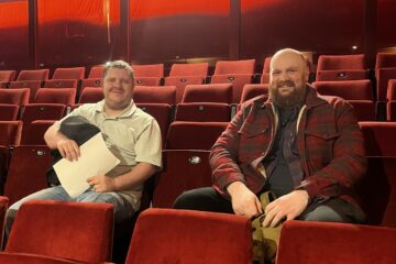 Two young men sat in the audience in an empty theatre.
