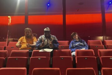 Two young men and a young woman sat in the audience in an empty theatre
