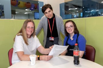 Three ladies sat at a table having a meeting