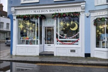 Exterior photo of the shop with blue colour contrasts for the visually impaired around the doors. This is a wide shot taken from the other side of the street.