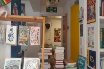Interior photograph of Maldon Books before sensory access audit view from the till. There are piles of books hanging card displays.