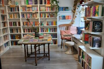 Interior photo of Maldon Books after the accessibility improvements - view of book shelves and reading nook with table in the middle of the floor featuring book displays.