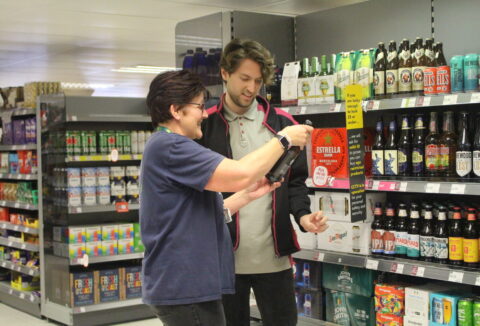 ECL customer Zach with Co-op worker looking at bottled drink product in the drink section.