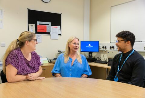 three adults, two female, one male in a meeting at work.
