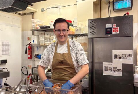 Young man with glasses working in a restaurant kitchen.