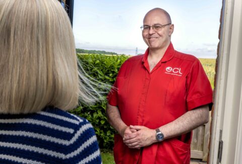 Male ECL carer in red uniform at front door of female customer.
