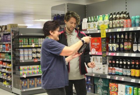 A man and a woman looking at a bottle of wine in Coop.