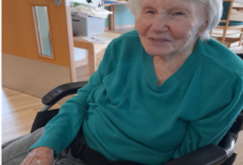 Lady smiling in a wheelchair at a day centre.