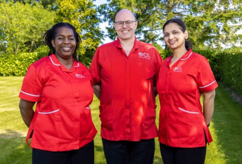 Two female and a male care worker in red ECL uniforms
