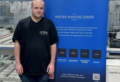 A young man standing next to a blue banner that shows Iceni's logo