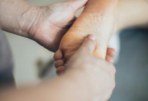 A close up picture of a hand doing physio exercises on a foot.