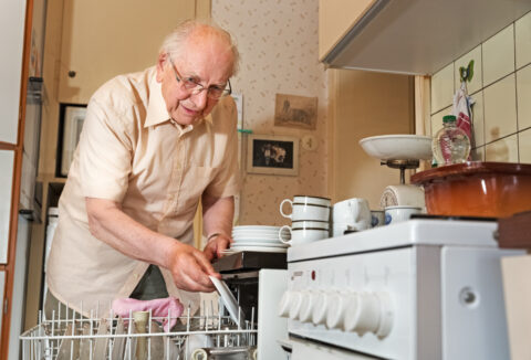An elderly man cleaning the dishes
