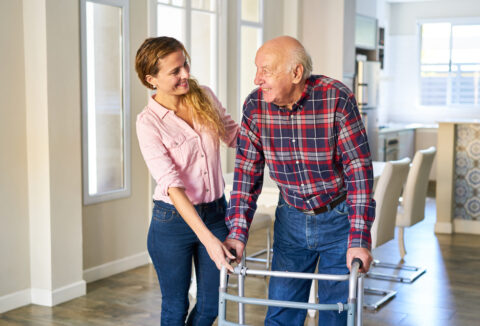 A woman helping an elderly man walk